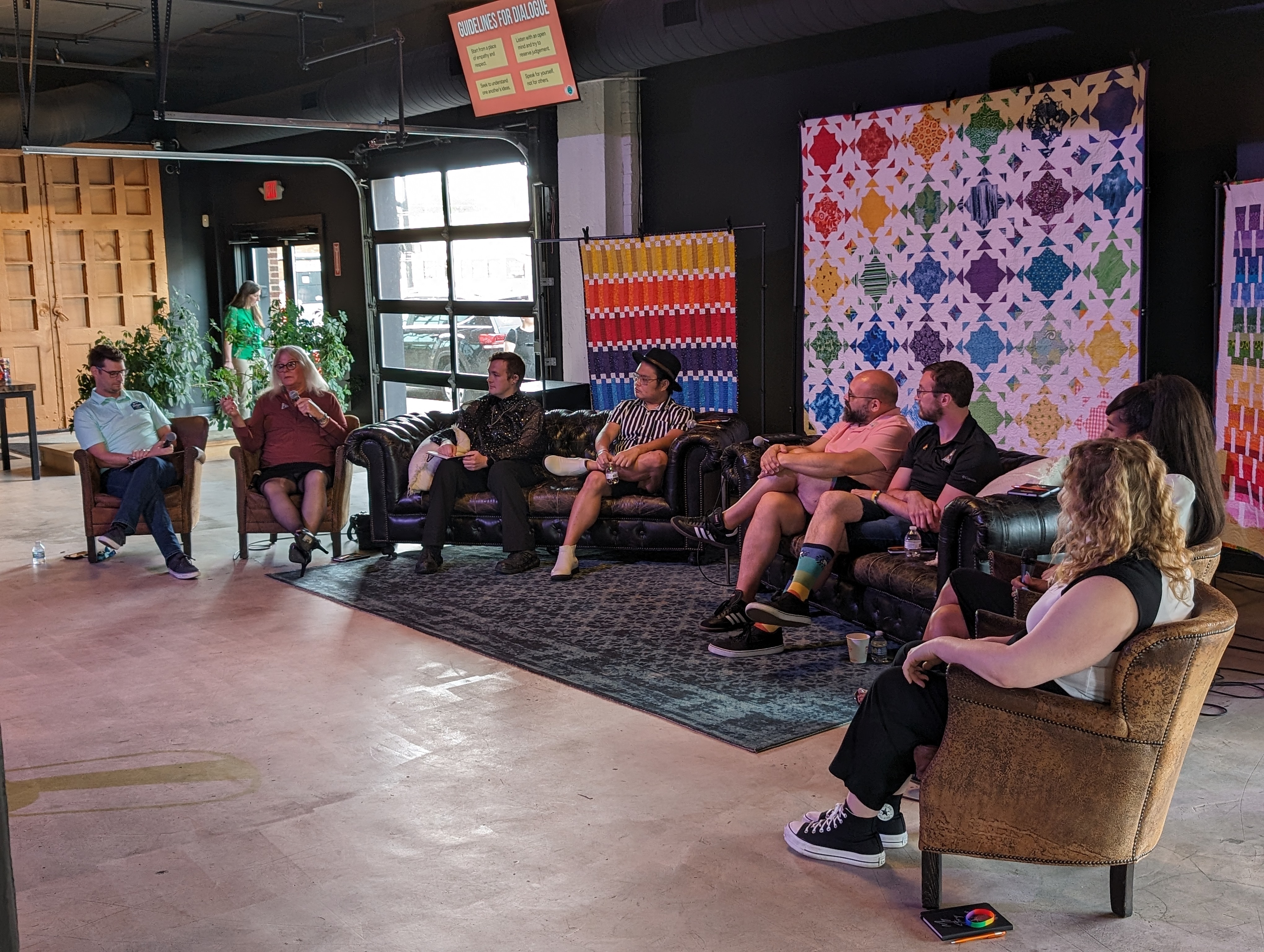 A group of people seated on couches and chairs having a discussion.