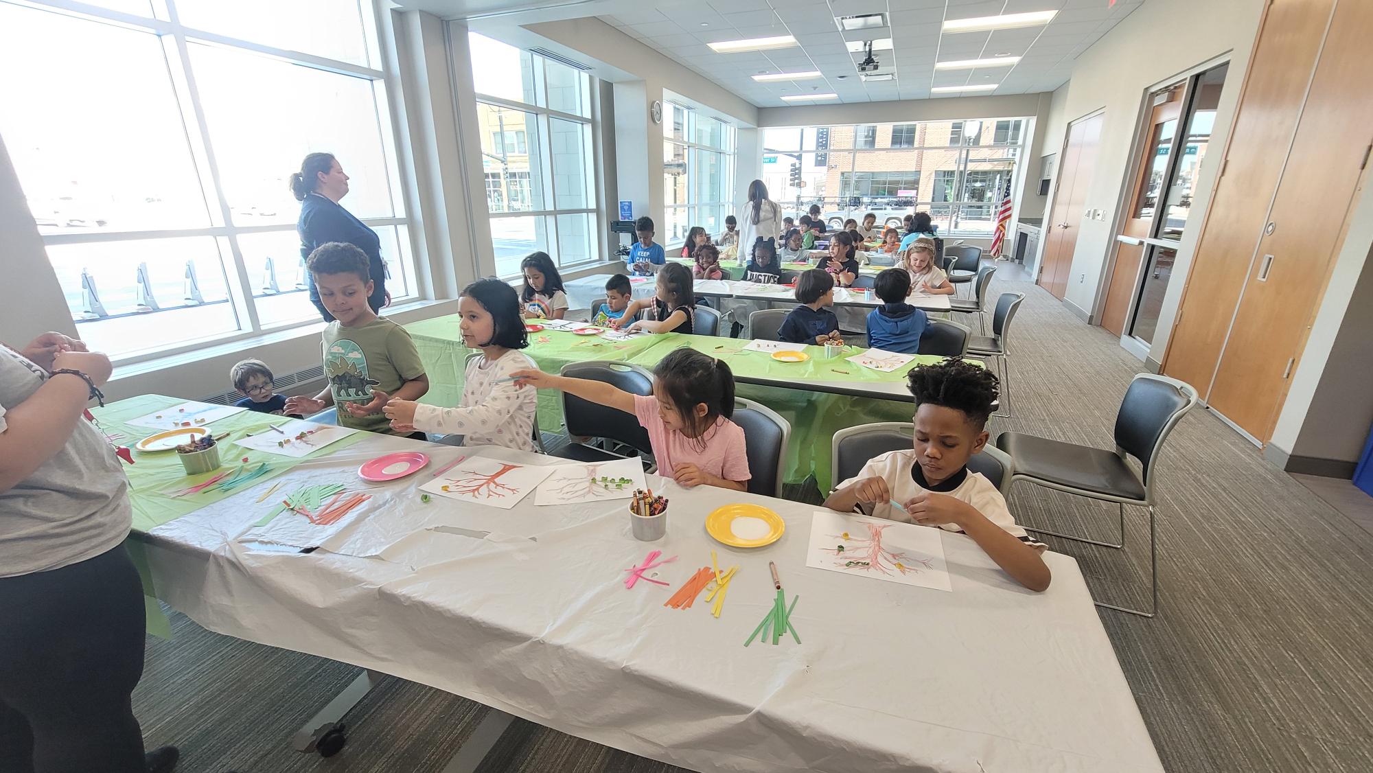 Children sit at rows of tables during a library school visit.