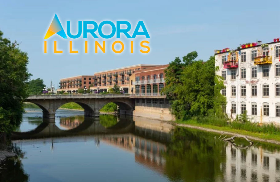 Exterior shot of buildings alongside the Fox River with a bridge across. Text reads Aurora Illinois in blue and yellow font.