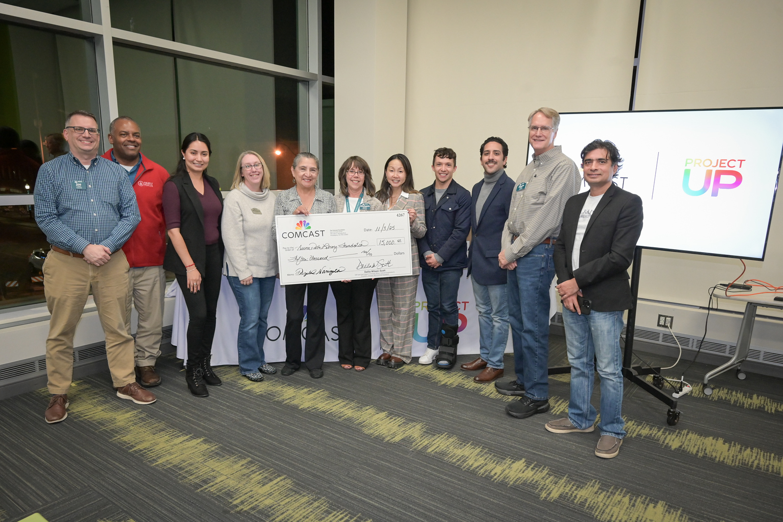 Event attendees gather for a group photo with a large check made out to the library for $15,000.