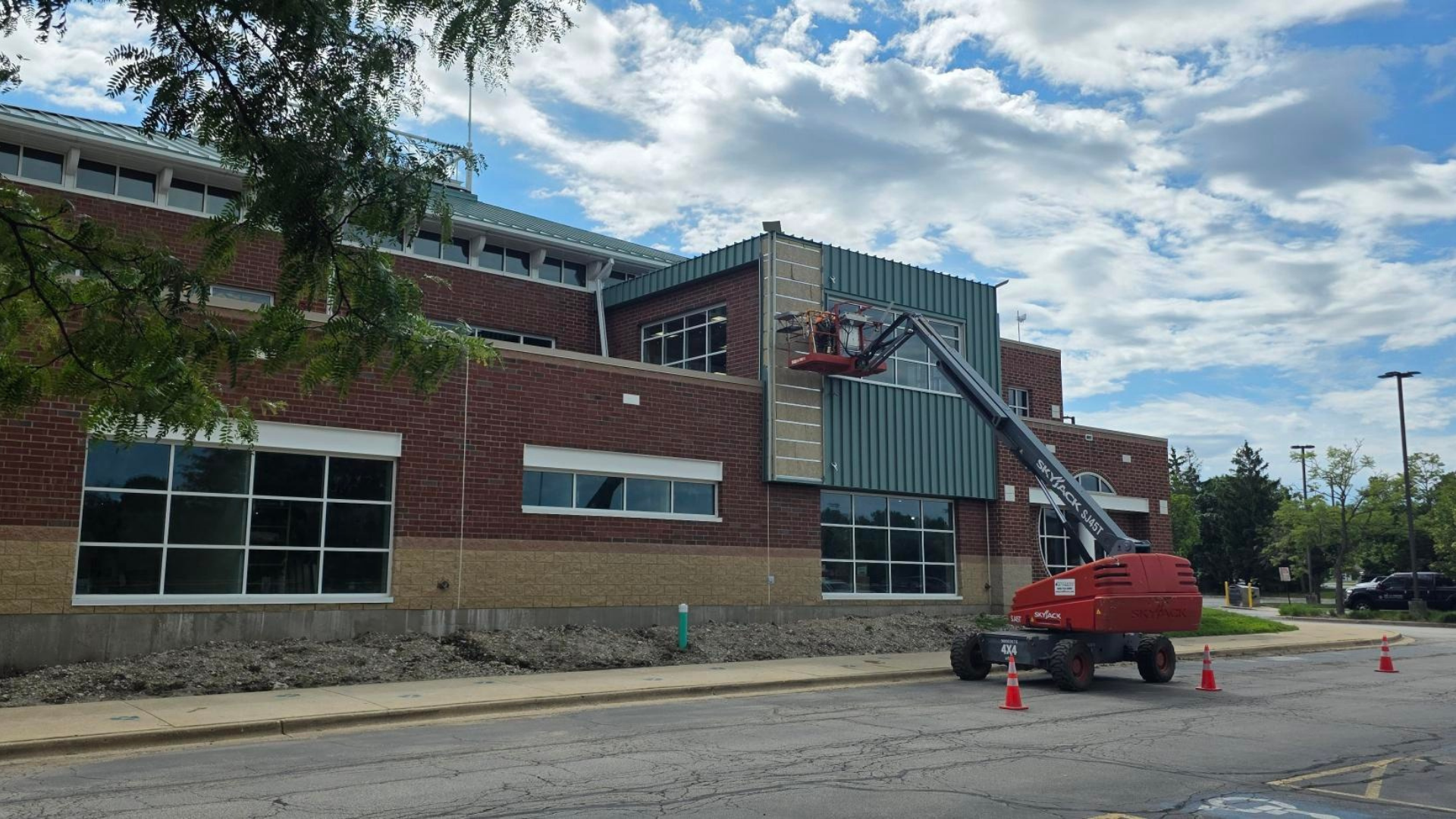 Construction equipment installs dark green metal finishes on the west side of the Eola Road Branch's brick exterior.