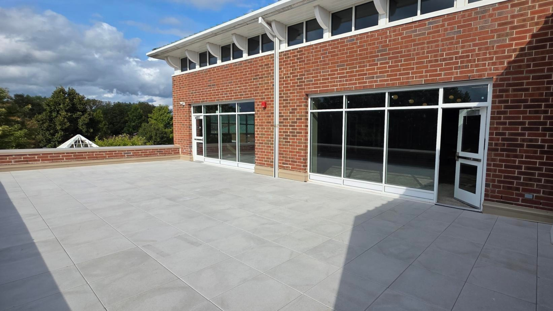 Completed pavers on second floor terrace of red brick Eola Road Branch building with white trimmed doors.